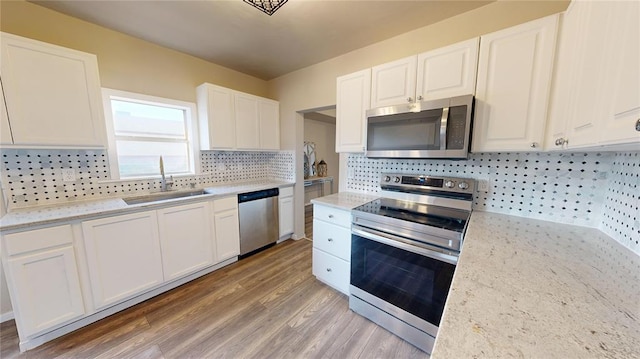 kitchen with sink, decorative backsplash, light wood-type flooring, appliances with stainless steel finishes, and white cabinetry