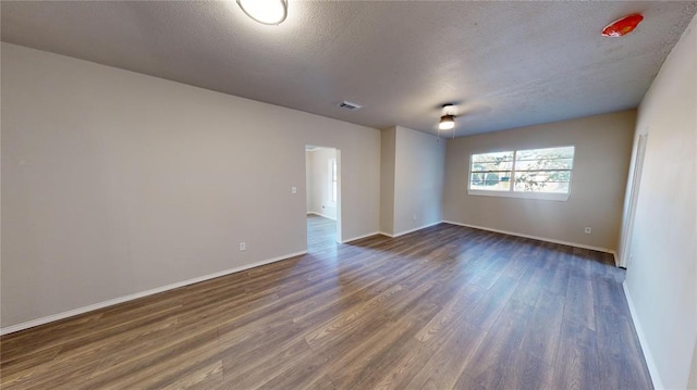 empty room featuring a textured ceiling and dark hardwood / wood-style flooring