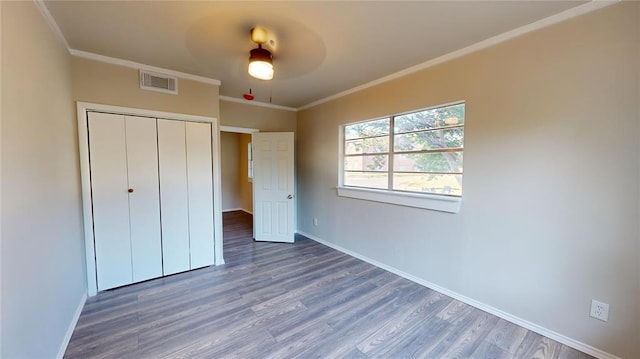 unfurnished bedroom with ceiling fan, a closet, crown molding, and dark hardwood / wood-style floors