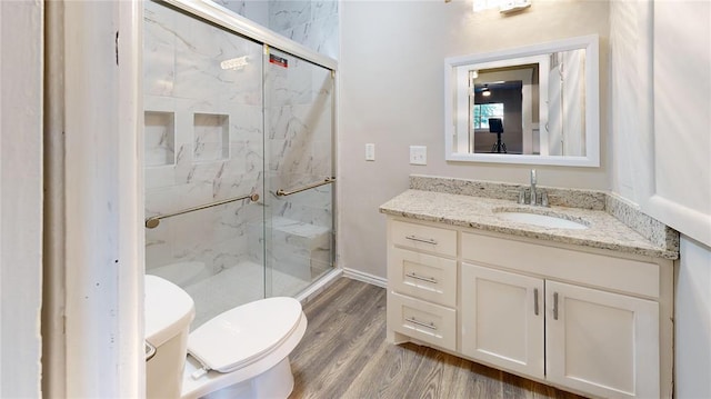 bathroom featuring vanity, toilet, wood-type flooring, and walk in shower