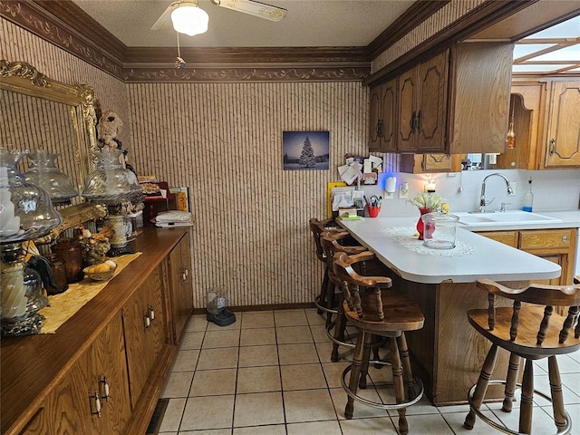 kitchen featuring kitchen peninsula, a skylight, sink, light tile patterned floors, and a breakfast bar area