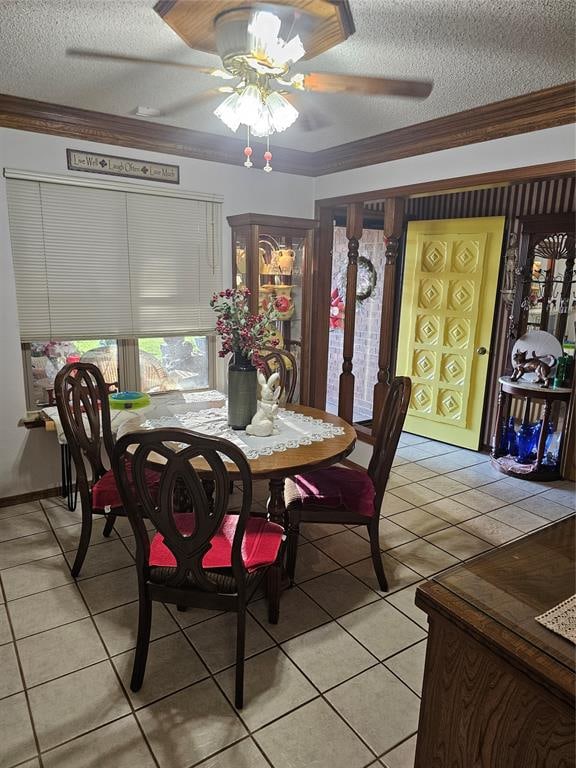 tiled dining room featuring ceiling fan, ornamental molding, and a textured ceiling