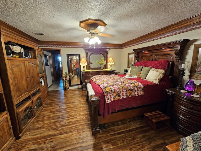 bedroom with a textured ceiling, crown molding, ceiling fan, and dark wood-type flooring