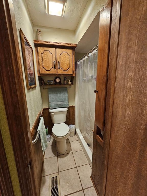 bathroom with tile patterned floors, a shower with shower curtain, and toilet