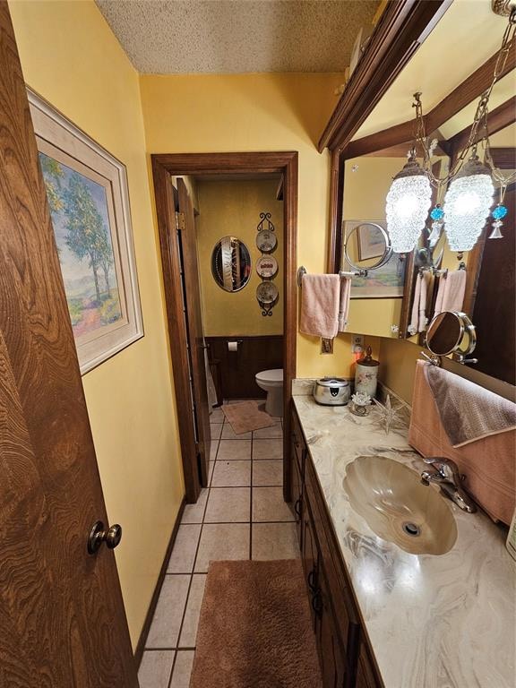 bathroom featuring tile patterned floors, vanity, toilet, and a textured ceiling