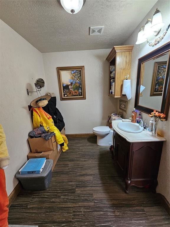 bathroom featuring hardwood / wood-style flooring, vanity, toilet, and a textured ceiling