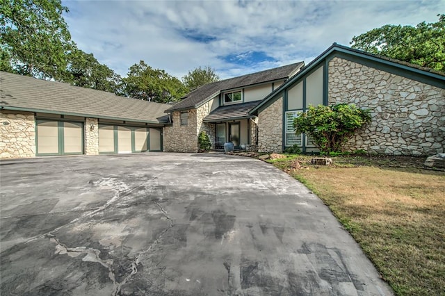 english style home featuring a garage and a front lawn