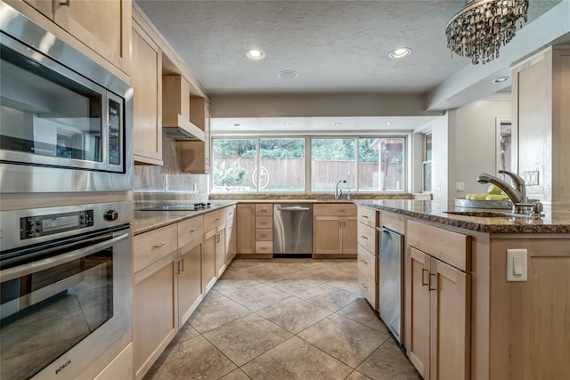 kitchen featuring light brown cabinets, sink, stainless steel appliances, a textured ceiling, and stone countertops