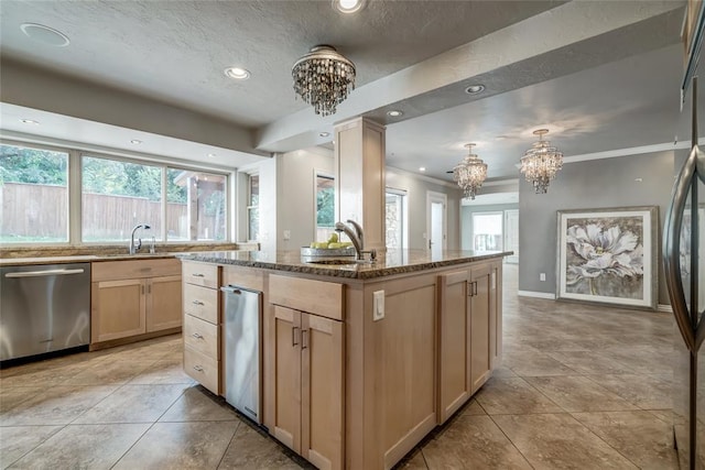 kitchen featuring light brown cabinets, a kitchen island with sink, crown molding, appliances with stainless steel finishes, and a notable chandelier