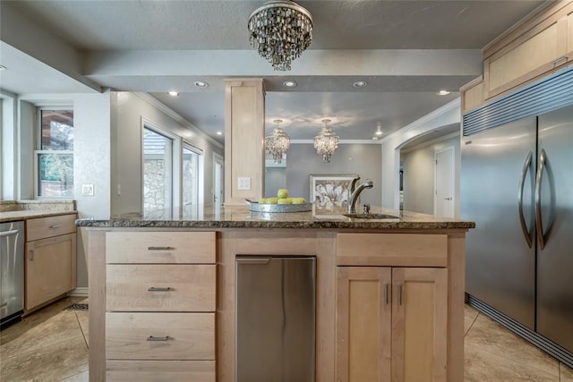 kitchen with light brown cabinets, stainless steel appliances, an inviting chandelier, and sink