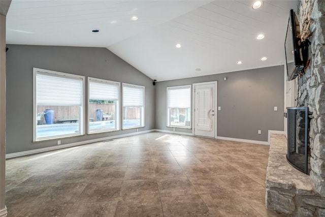 unfurnished living room featuring a stone fireplace and lofted ceiling