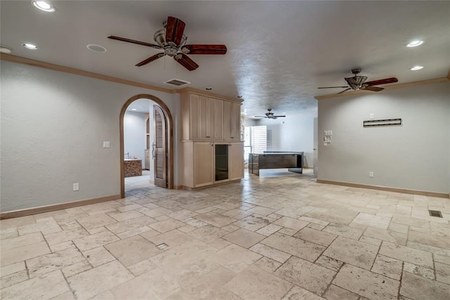 unfurnished living room with ceiling fan and crown molding