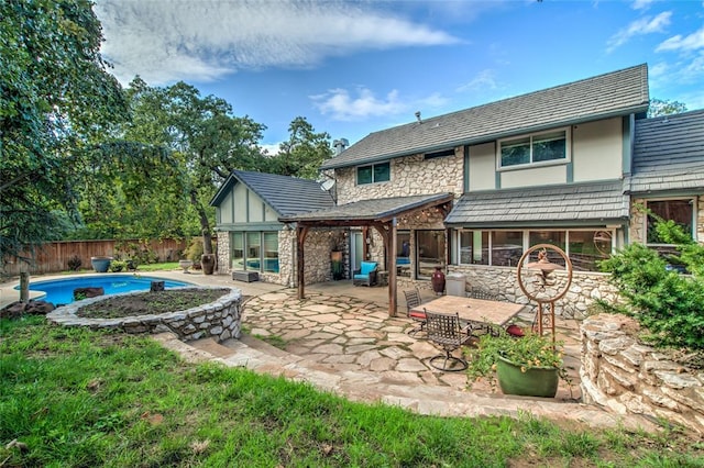 rear view of property featuring a fenced in pool and a patio