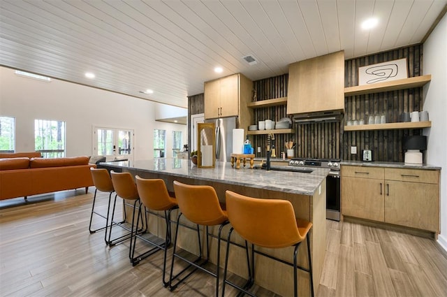 kitchen with light wood-type flooring, wood ceiling, stainless steel appliances, a kitchen island with sink, and exhaust hood