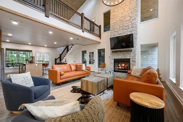 living area with a high ceiling, a fireplace, wood finished floors, visible vents, and stairs