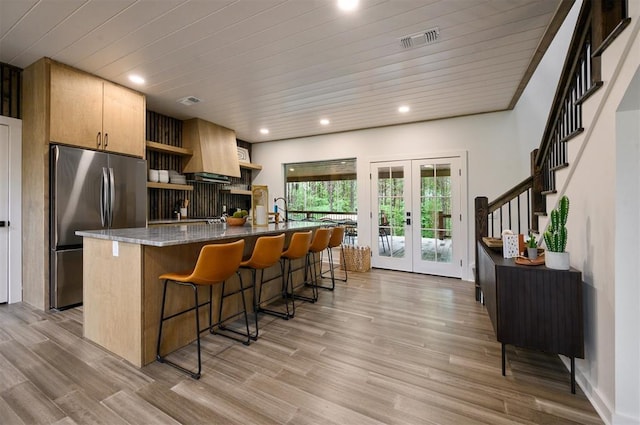 kitchen featuring a breakfast bar area, visible vents, french doors, freestanding refrigerator, and open shelves