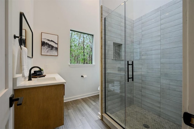 bathroom with toilet, wood finished floors, vanity, baseboards, and a shower stall