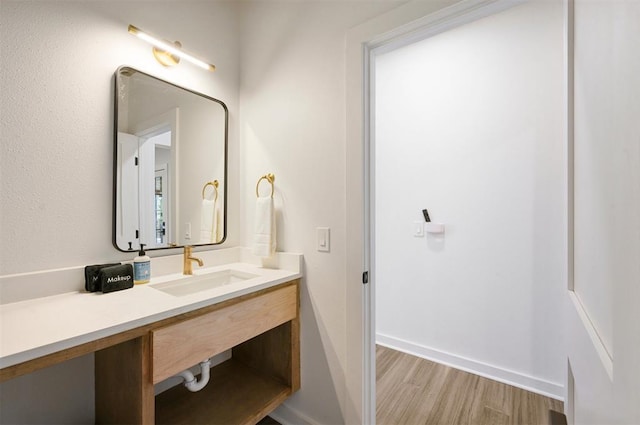 bathroom with wood finished floors, vanity, and baseboards