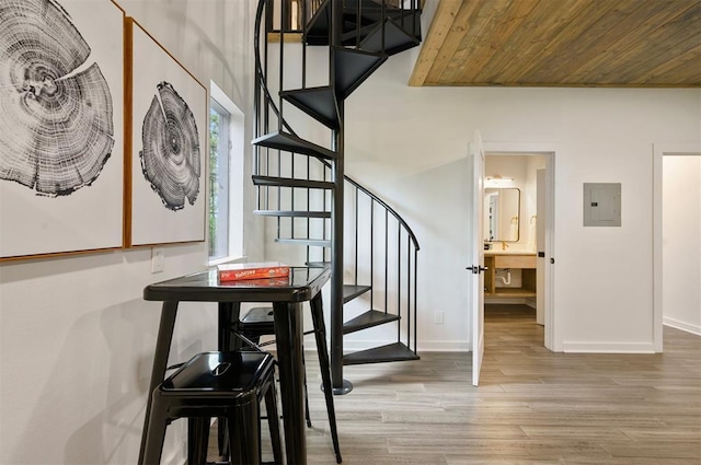 stairs with wood ceiling, electric panel, baseboards, and wood finished floors