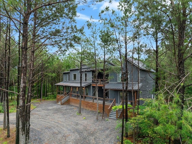 view of front of home featuring metal roof, driveway, and stairs