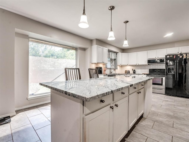 kitchen featuring light stone countertops, appliances with stainless steel finishes, sink, pendant lighting, and white cabinets