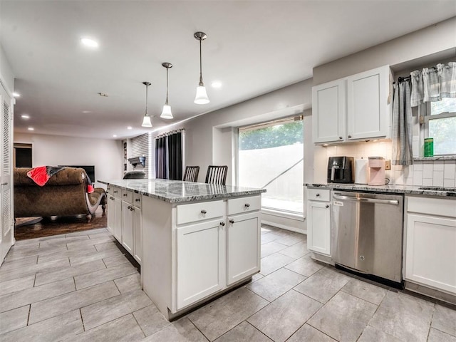 kitchen with hanging light fixtures, stainless steel dishwasher, light stone countertops, a kitchen island, and white cabinetry