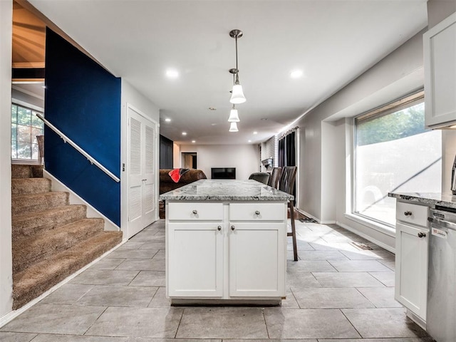 kitchen with a wealth of natural light, white cabinets, decorative light fixtures, and a kitchen island