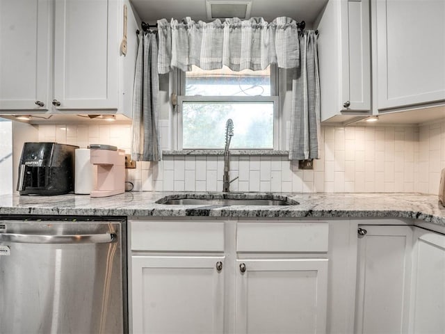 kitchen with dishwasher, white cabinets, light stone countertops, and sink