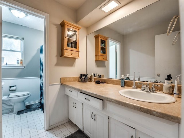 bathroom with tile patterned floors, vanity, toilet, and curtained shower