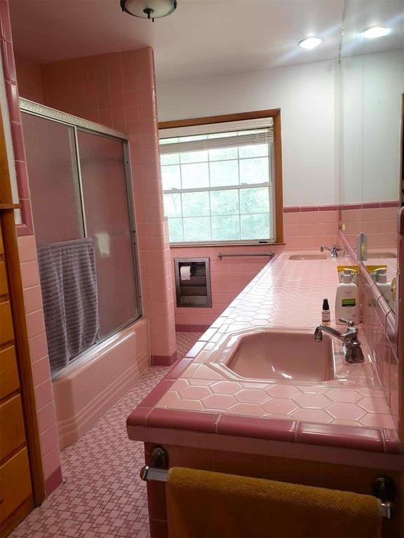 bathroom featuring combined bath / shower with glass door and vanity