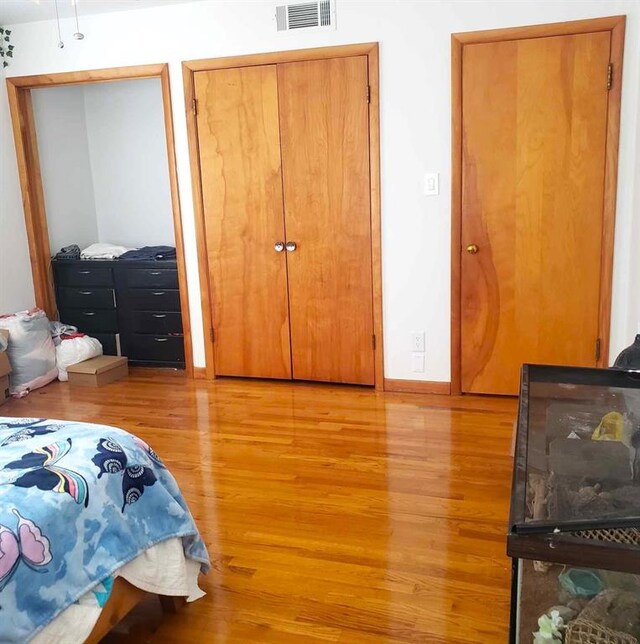 bedroom with two closets and light wood-type flooring