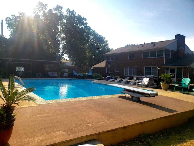 view of swimming pool with a patio area and a diving board