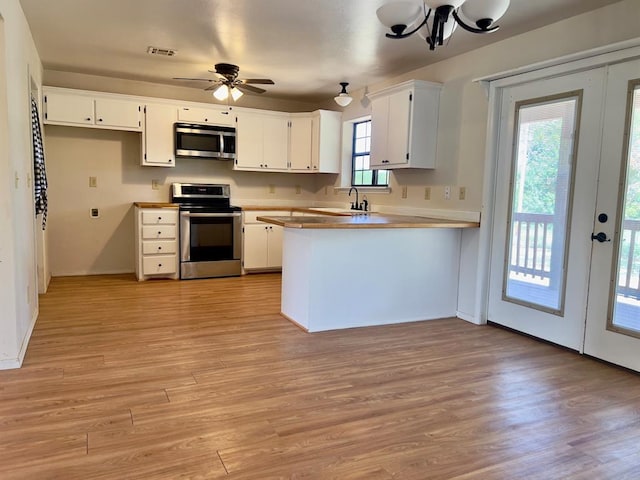 kitchen with kitchen peninsula, white cabinetry, light hardwood / wood-style flooring, and stainless steel appliances