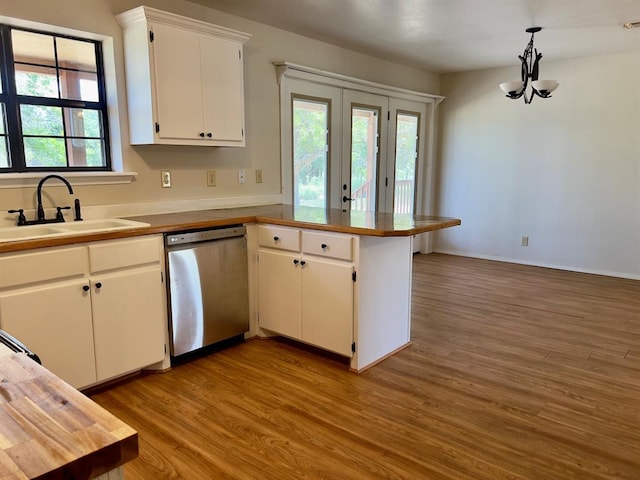 kitchen with stainless steel dishwasher, a wealth of natural light, sink, decorative light fixtures, and white cabinets