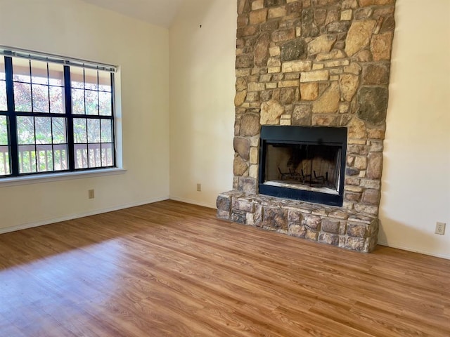 unfurnished living room featuring hardwood / wood-style floors and a stone fireplace