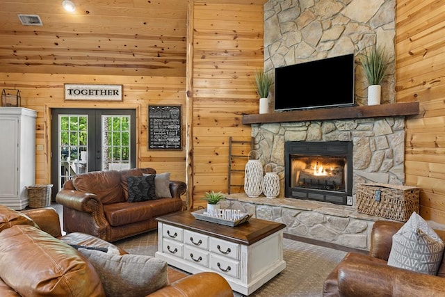 living room featuring a fireplace, french doors, and wood walls