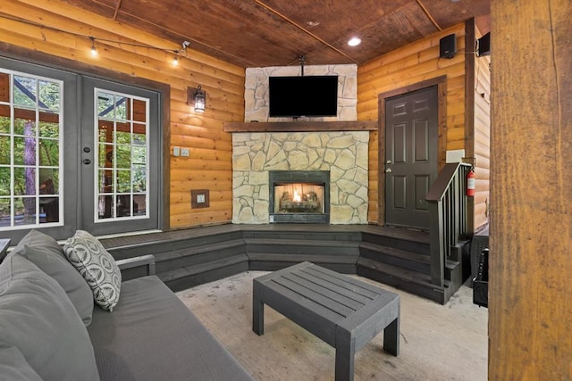 living room with a stone fireplace, log walls, and wooden ceiling