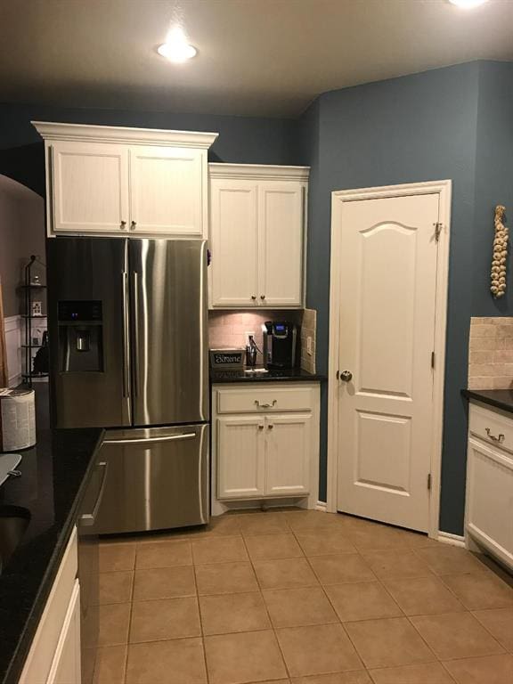 kitchen with white cabinets, decorative backsplash, and stainless steel refrigerator with ice dispenser