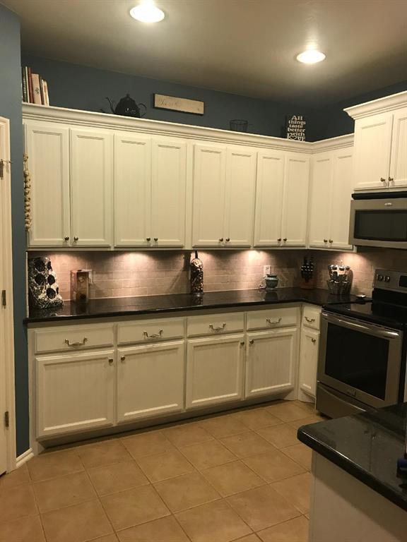 kitchen featuring decorative backsplash, appliances with stainless steel finishes, white cabinets, and light tile patterned flooring