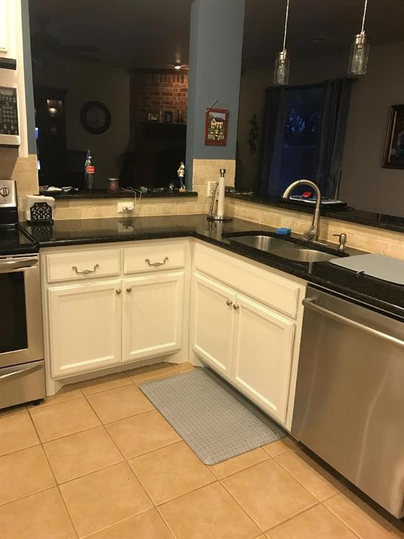 kitchen featuring hanging light fixtures, sink, light tile patterned floors, and stainless steel appliances