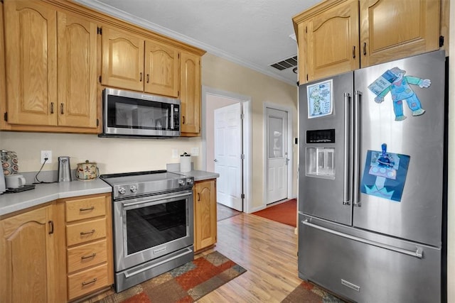 kitchen with stainless steel appliances, light hardwood / wood-style flooring, and ornamental molding