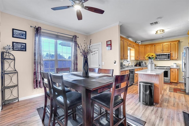 dining area featuring ceiling fan, light hardwood / wood-style floors, crown molding, and sink