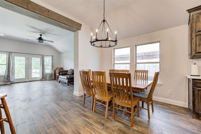 dining space featuring vaulted ceiling with beams, wood-type flooring, and ceiling fan with notable chandelier