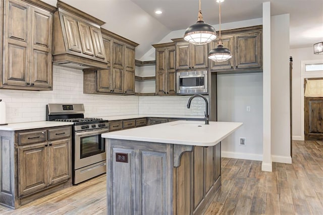 kitchen featuring a center island with sink, sink, custom range hood, and stainless steel appliances