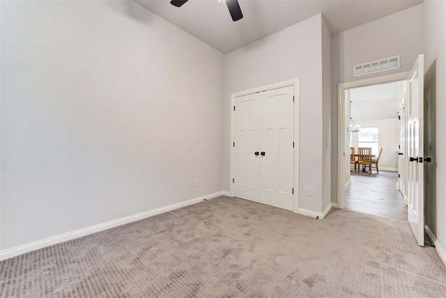 unfurnished bedroom with ceiling fan, a closet, and light carpet