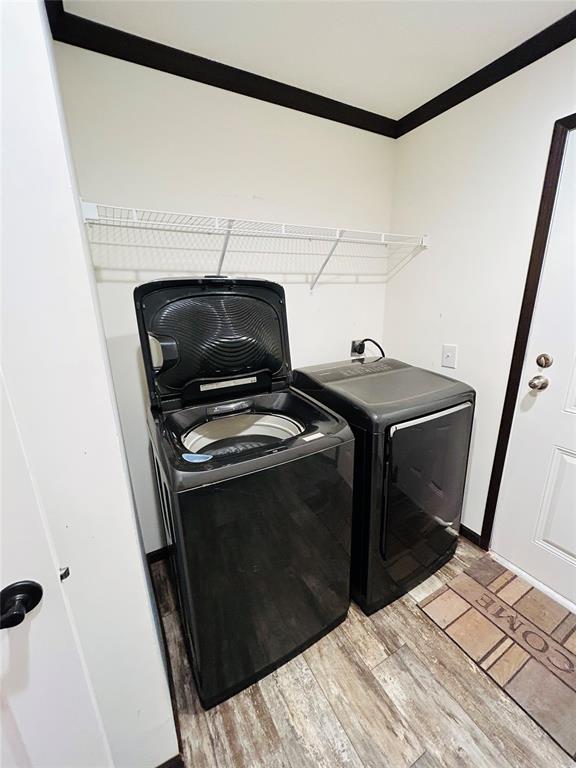 washroom featuring washer and clothes dryer, light wood-type flooring, and ornamental molding