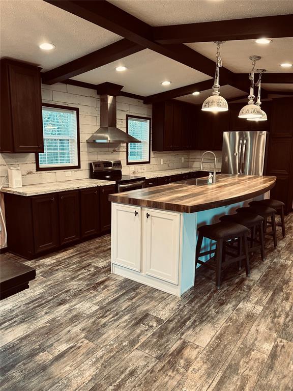 kitchen with stainless steel appliances, extractor fan, butcher block countertops, beamed ceiling, and dark hardwood / wood-style floors