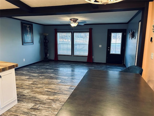 interior space with dark hardwood / wood-style flooring, ornamental molding, a textured ceiling, ceiling fan, and beamed ceiling