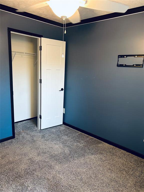 unfurnished bedroom featuring a closet, a textured ceiling, and dark colored carpet