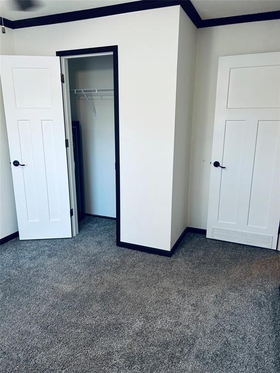 unfurnished bedroom with dark colored carpet and a closet